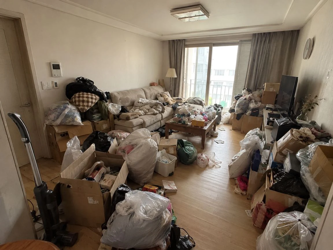 부천 쓰레기집청소 거실 소파와 탁자 주변에 봉투·상자와 생활 물품이 놓여 있습니다.
